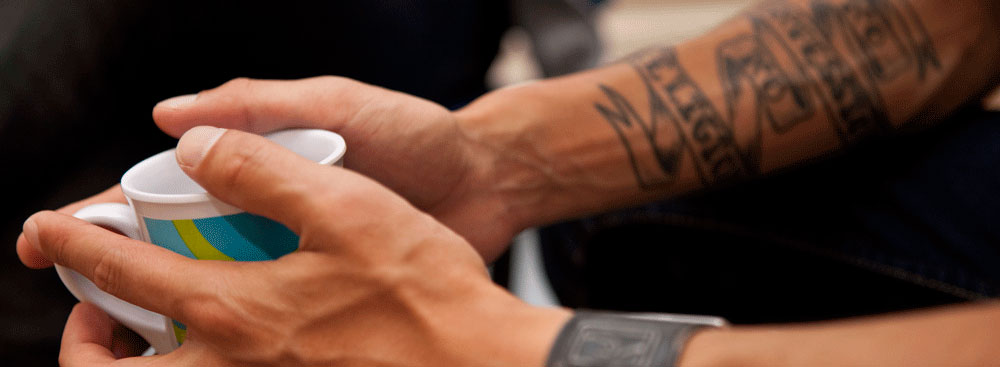 tattooed man holding coffee
